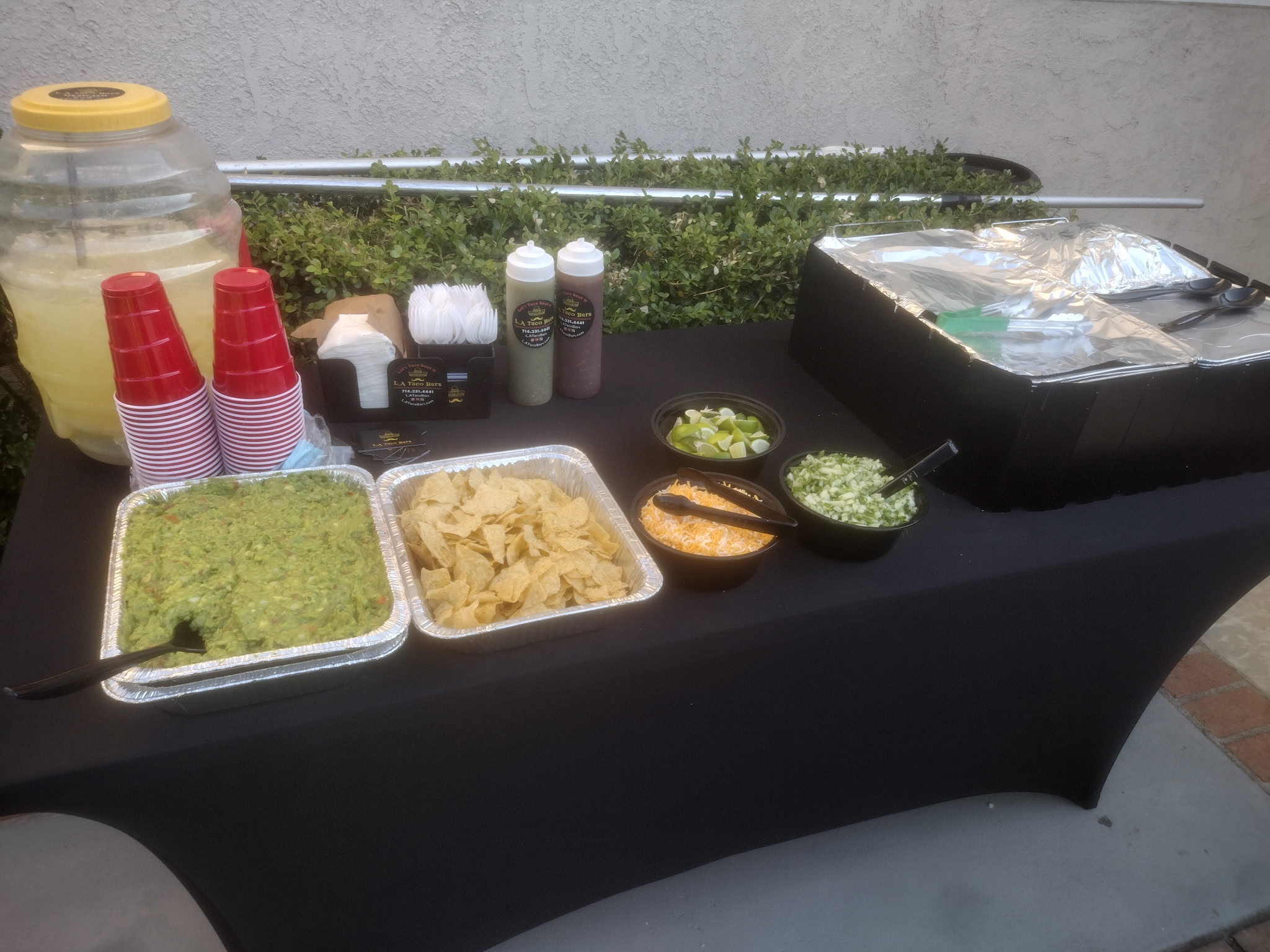 Taco catering table with guacamole, chips, beverages, and supplies