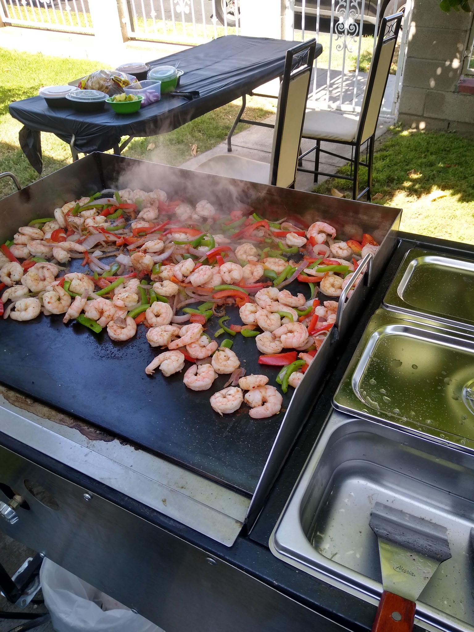 Shrimp, peppers, and onions cooking on a catering grill